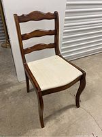Full view of vintage wooden chair showing carved scalloped back, curved legs and upholstered seat.