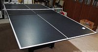 Black ping pong tabletop assembled on air hockey base with net attached