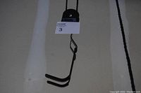Close-up image of black metal hooks with rubber coating for holding bicycle frame, suspended by pulley ropes.