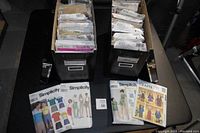 Two metal Ikea pattern boxes filled with assorted sewing pattern envelopes arranged vertically, mostly from Simplicity, Butterick, and McCall.