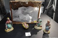 Ceramic nativity figures displayed with a wooden stable partially filled with wrapping material.