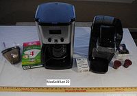 Photo of both coffee makers with accessories arranged on tabletop, ruler for scale