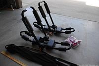 Two Field & Stream kayak carriers laid on the floor with straps and red accessories beside them