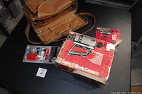 Camera with original packaging box, camera case, and accessories on table.