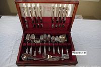 Top-down view of entire silverplate flatware set arranged in the wooden box showing the full complement of knives, forks, and spoons for eight.
