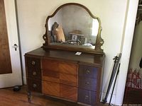 Front view of vintage wooden dresser with attached arched mirror, showcasing the wood grain pattern on the drawers and overall condition.