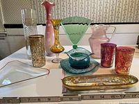 Wide shot showing full assortment of colorful Bohemian glass vases, pitchers, tumblers, and trays on a table