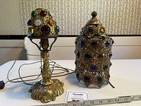 Full view of metal lamp with small jeweled shade on the left and separate ornate jeweled shade on the right, ruler for scale.