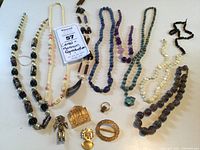 Full lot overview showing various beaded necklaces and pins laid out on flat surface.