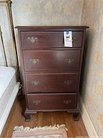 Front view of the chest showing four drawers and metal handles, dimensions and lot tag attached.