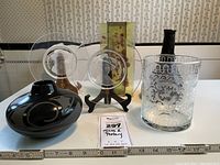 Full lot showing two clear etched glass plates, one modern stained glass panel with vase, etched glass cylinder, black rustic bottle, and dark Native American style pottery vase.