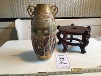 Nippon vase and fish bowl stand displayed on white table, showing full vase front with painted landscape and gold accents, and wooden stand with round top and curved legs