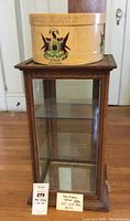 Full view of wooden display case with glass shelves and Knox hat box on top