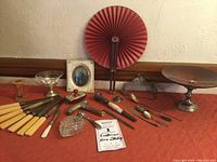 Wide shot of all lot items on red cloth with fan, portrait, and compote
