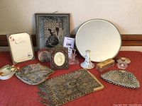 Photo showing an array of vintage Victorian ladies items on a red surface including small bags, perfume bottles, hat pin holder, picture frames, and a small dish.