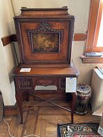Front view of vintage or antique wooden drop front desk with Regency style painted illustration on front panel showing a classical scene. Desk has carved decorative trim and slender legs.