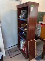 Full view of 4-tier wooden bookcase with some Christmas decor and household items on lower shelves.