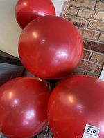 Close-up of three large red spherical balloons on the fixture showing smooth surface and weathered condition.