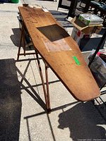 Full top view of antique wooden ironing board showing tapered shape and foldable legs.