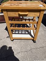 Front view of wooden rolling chopping block island showing drawer, slatted lower shelf, and caster wheels