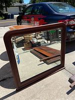 Photo of rectangular beveled edge mirror with wooden frame, scratches visible, reflecting outdoor scene with car.