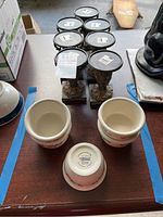 Photo showing five Corelle stoneware bowls and seven European-style pillar candle holders on a table.