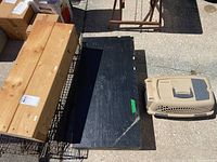 Photo showing the large Critter Catcher cage wire and wood construction and nearby Petmate pet carrier and wood podium panels on ground.