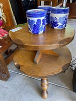 Three blue and white ceramic canisters with grapevine motif on a two-tier wooden end table placing in garage space