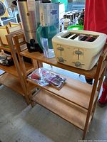 Wooden fold-up display shelf with the BRITA pitcher, Oster toaster, and lighters on top and middle shelf