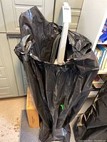 Black bag containing several white plastic attachments for the Hoover Steam-Vac steam carpet cleaner. The bag catch handle or pole of an attachment.
