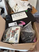 Photo showing box with old cell phones including Nokia in packaging, carrying cases, and accessories