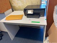 Photo of white MDF office desk with HP Photosmart 6520 printer placed on top. Desk has pull-out keyboard shelf visible beneath surface.