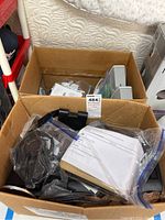 Box containing various electronic items and accessories including Logitech keyboard, cables, and packaged items