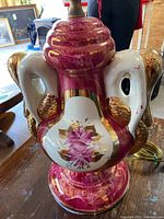 Close-up of the magenta lamp base showing floral decoration, 24kt gold trim accents, and mermaid arm sculptural details.