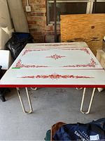 Top view of table showing white metal surface with red floral stencil design