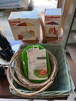 Photo showing boxed cocktail cart and condiment cart, green and white plastic dishware, and multiple wicker baskets.
