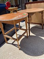 Photo showing two round wood tables, one with a veneer top and the other with a protective surface and decorative legs.