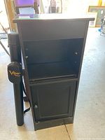 Photo of the small black wooden bookcase with door and shelves showing general condition