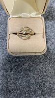 Front view of 18KT H.G.E. ring showing the three clear accent stones and design details in a presentation box.
