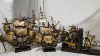 Side view of five model ships, showing detailed sails and rigging with visible wear and aged paint.