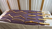 Photo showing 12 wooden hangers laid out on a purple towel, 6 shirt hangers on left side and 6 pants hangers with clips on the right side.