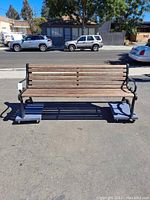 Front view of the DuMor Inc. park bench showing wooden seating slats and black metal frame.