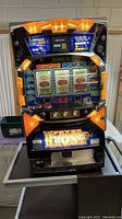 Front view of the Fever Ghost slot machine showing top and front lights, digital display, and coin/token slot.