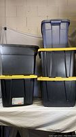 Front view of five large storage containers stacked in two columns. Three containers on left and two on right, showing lids and some visible labels and wear.