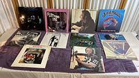 Top view of a purple cloth with 10 vinyl LP records displayed, showing album covers from Fleetwood Mac, Bob Dylan, Steve Miller Band, and others.
