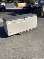 Lifetime deck storage box shown from the front with closed lid on pavement outdoors.