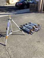View showing one assembled sprinkler on tripod with the other four tripods collapsed and lying down on the ground.