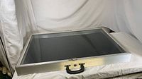 Closed display case lying flat, showing aluminium frame, glass top and black interior