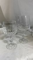 Pair of clear lead crystal glasses of different sizes showing cut crystal pattern and faceted stems