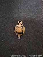 Front view of gold pendant showing detailed emblem and design